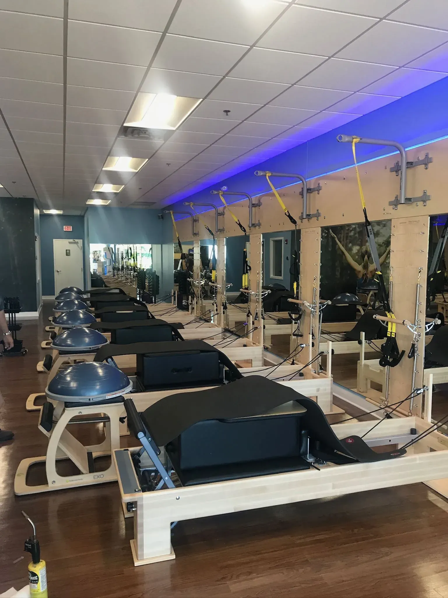 Pilates studio with rows of reformers under LED panel lighting