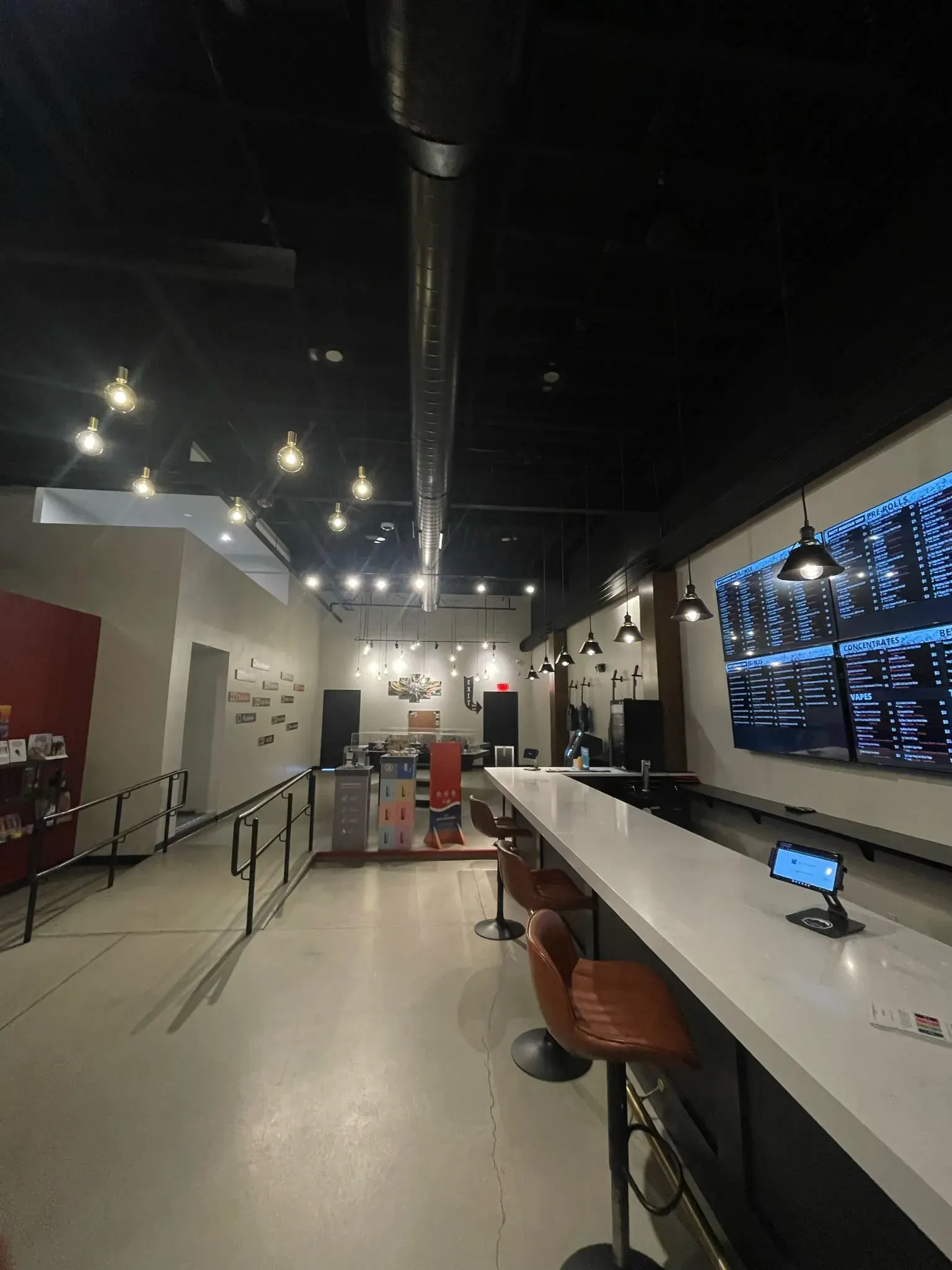 Long retail counter under an exposed black ceiling with pendant lights