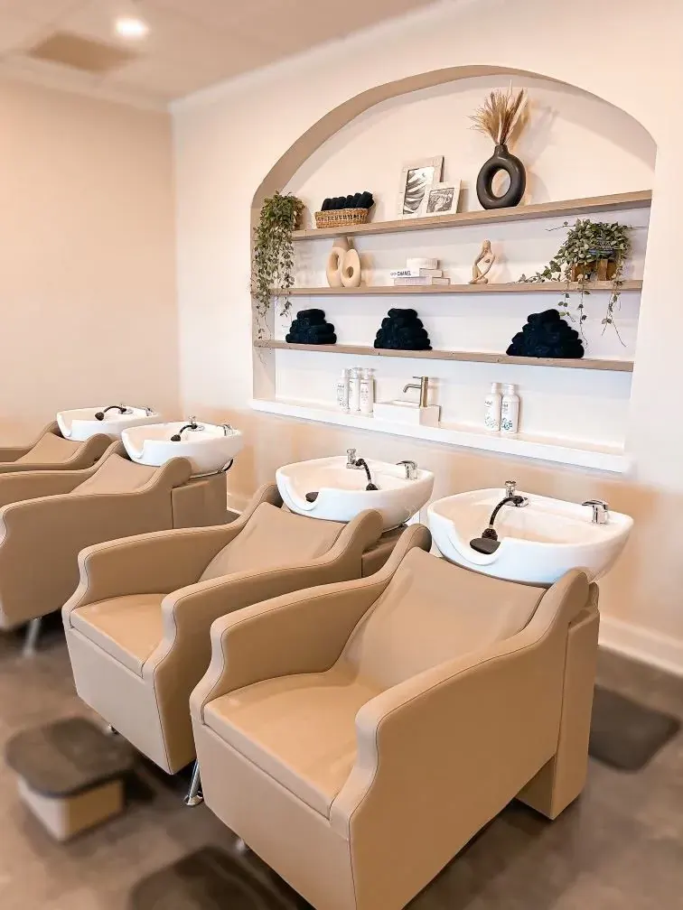 Salon shampoo chairs below a lit arched shelving niche
