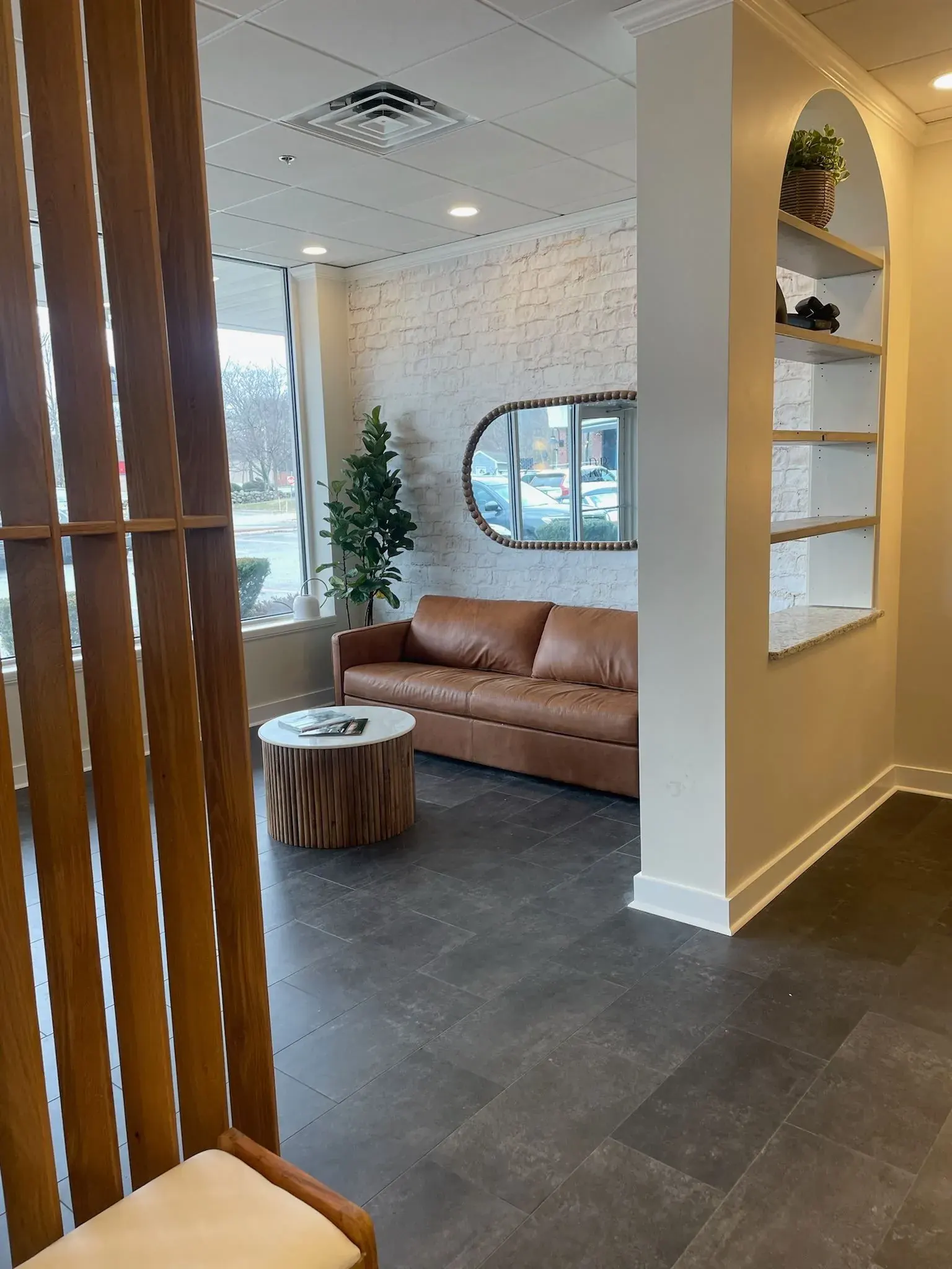 Salon waiting area with a leather sofa and lit shelving