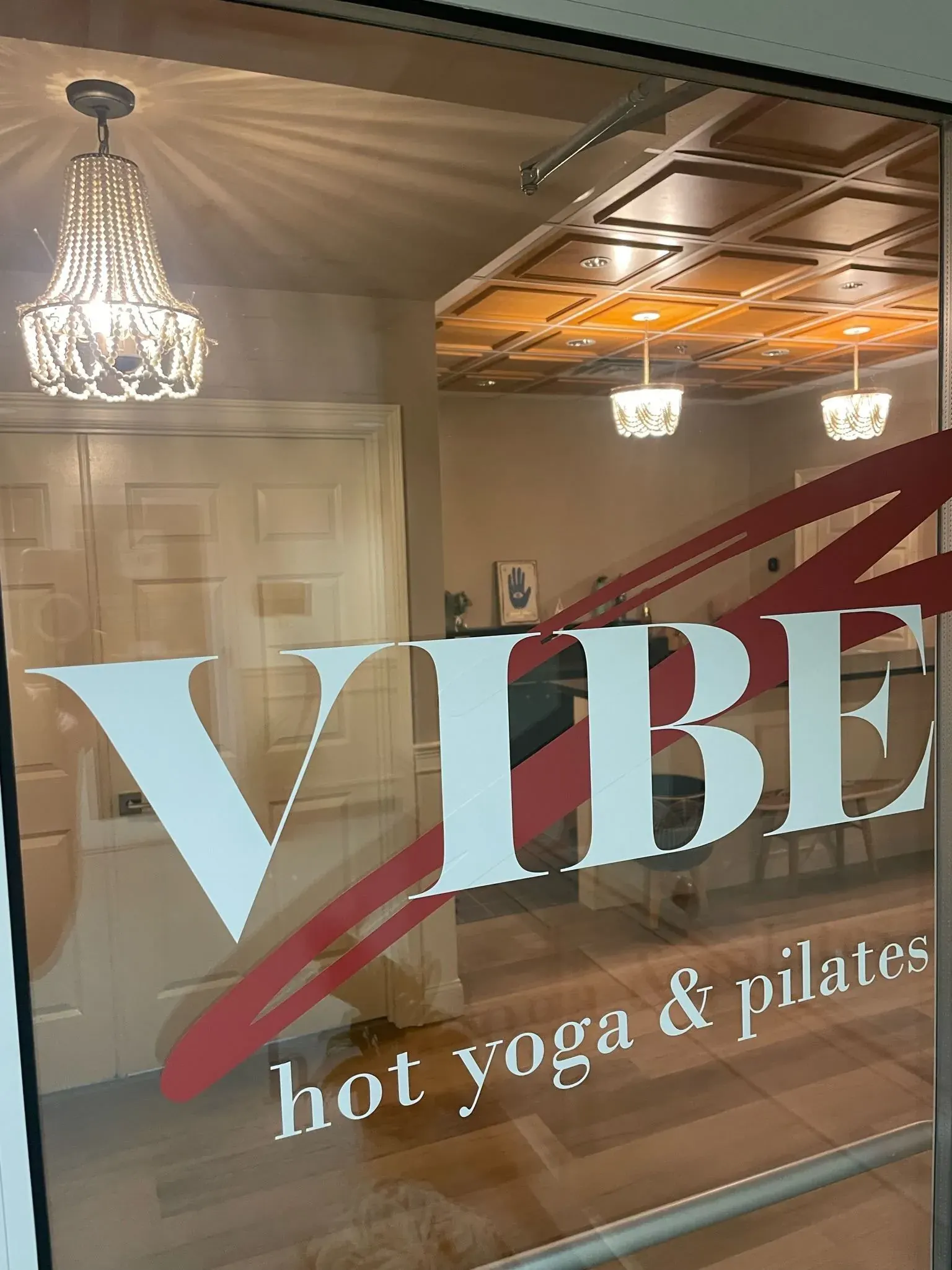 Studio entry with a beaded chandelier behind lettered glass