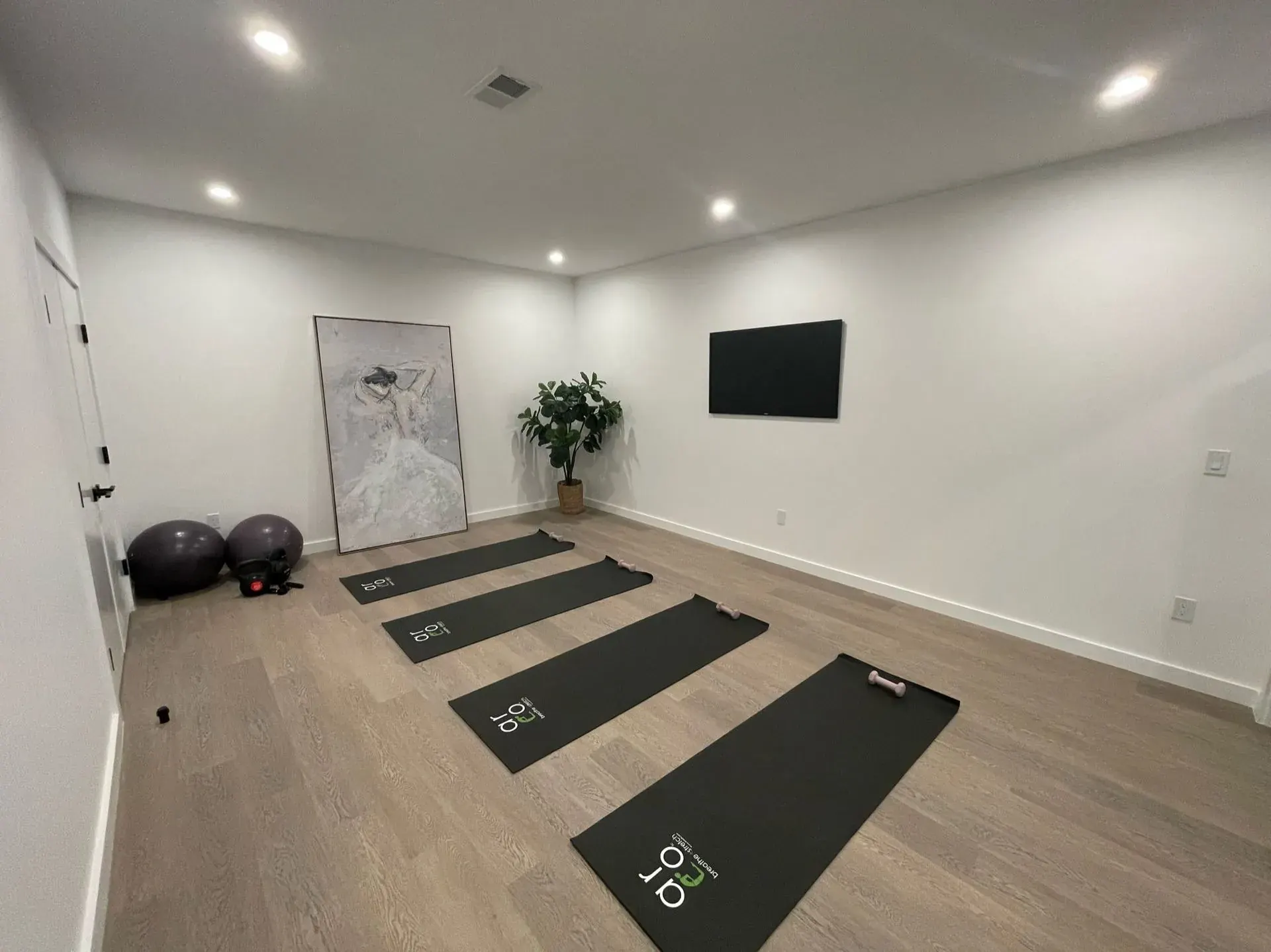 Small exercise room with recessed lights and a wall-mounted TV