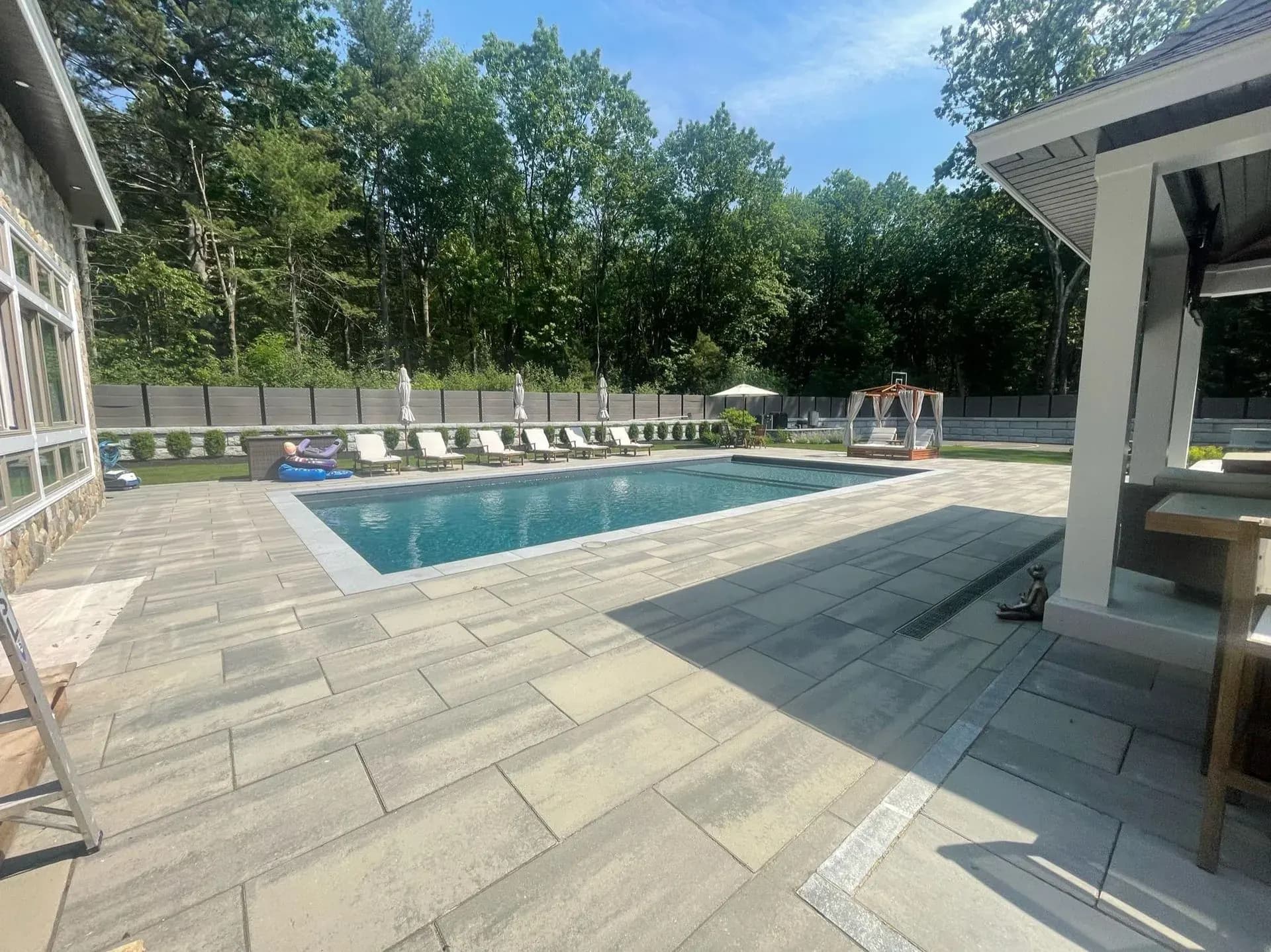 Pool deck with a paver patio beside a cabana