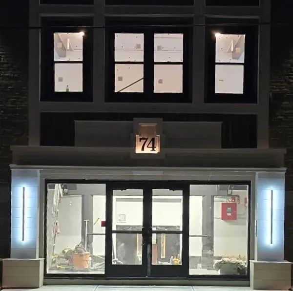 Storefront entry framed by vertical LED sconces at night