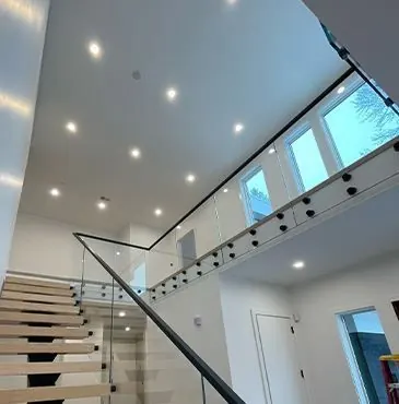 Floating stair with a glass rail under recessed lights