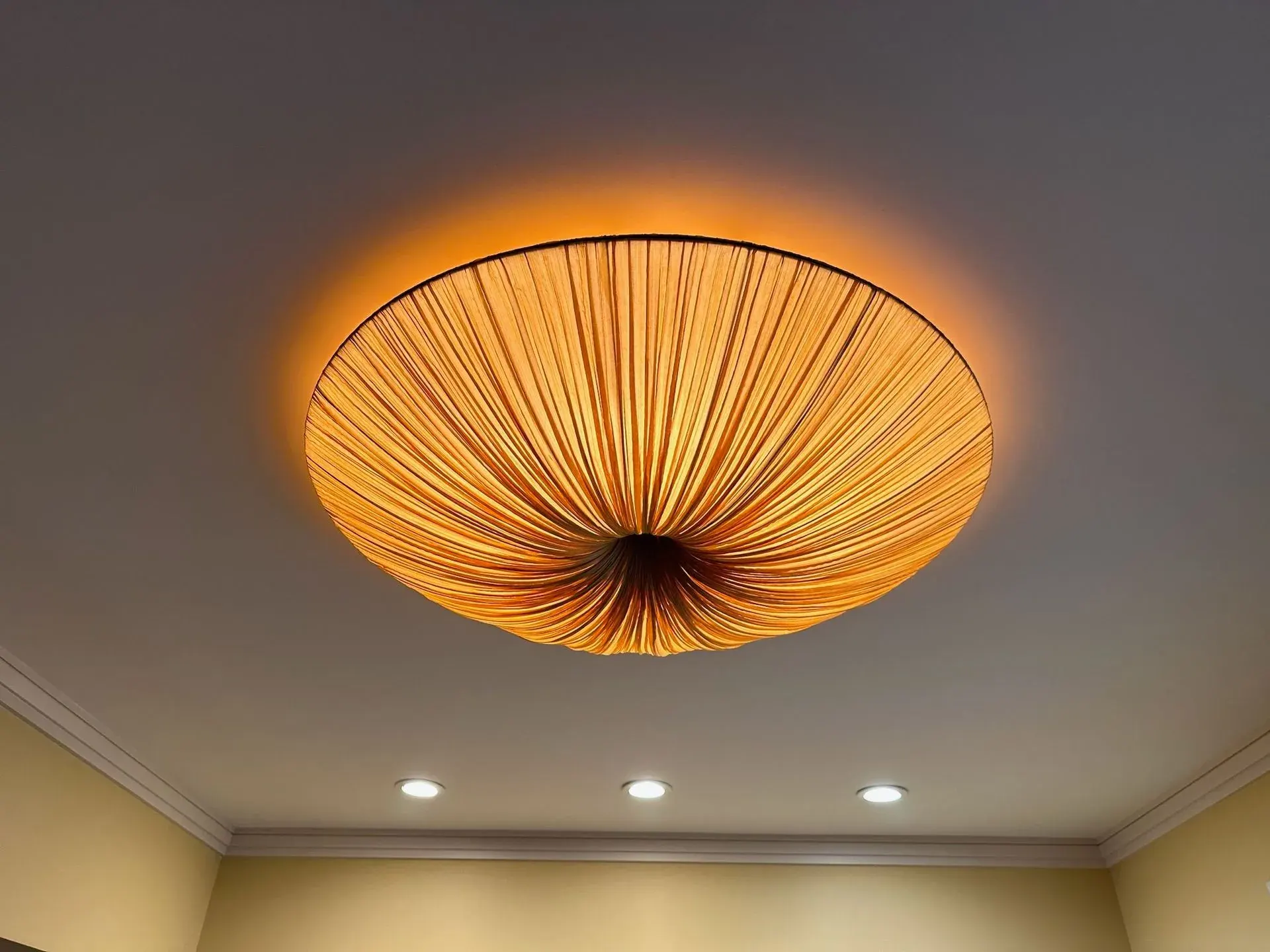 Pleated drum ceiling fixture glowing amber