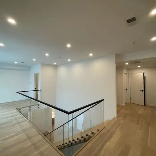 Recessed lights over an open stair landing with a glass railing