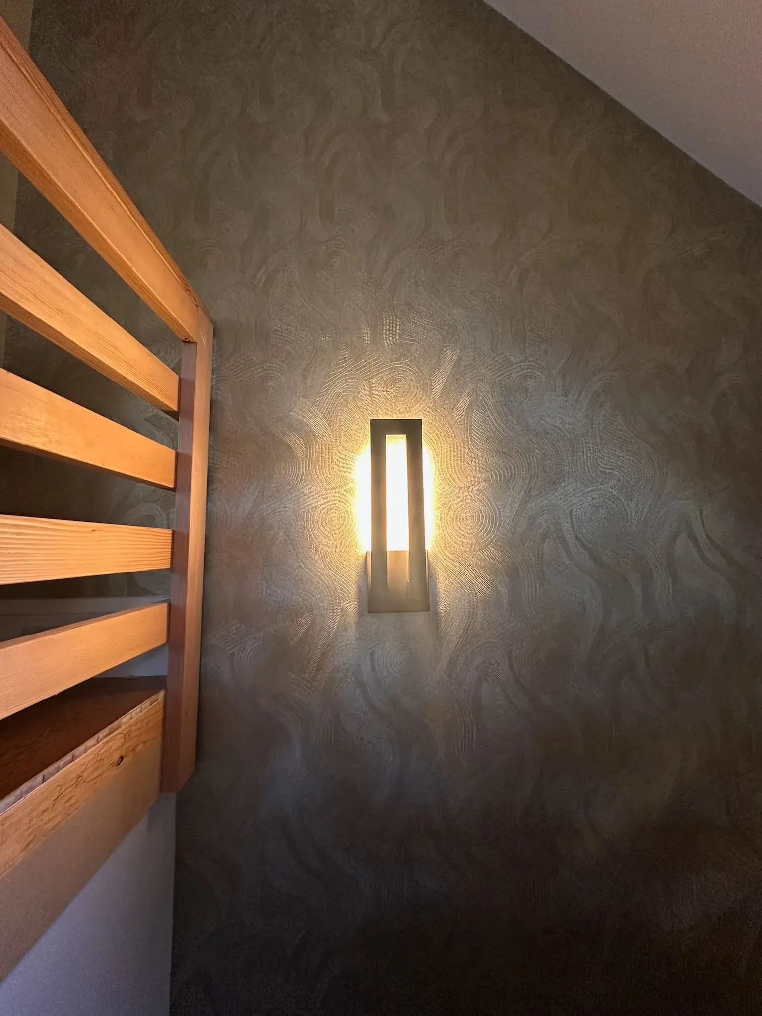 Vertical wall sconce on textured wallpaper